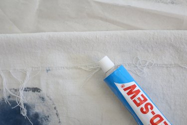 Use fabric glue or sew a seem at the bottom and top of canvas. Allowing space for the dowel to fit through.