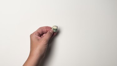 A single one-dollar bill folded five times to be about the size of a quarter
