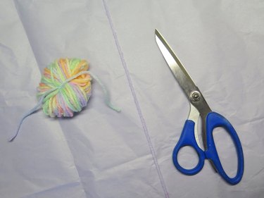 A bundle of yarn next to scissors with a blue handle