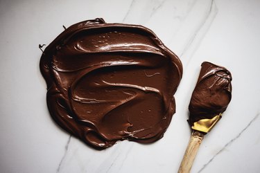Use the rubber spatula to mix the food dyes together to form a dark chocolate brown color.