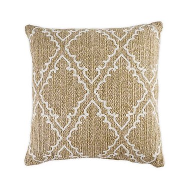 Square throw pillow with tan, natural-looking woven fabric with a pattern that resembles diamond cut-out shapes with curly edges.