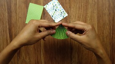 olding scrapbook paper to make a Christmas tree for DIY gift tags.