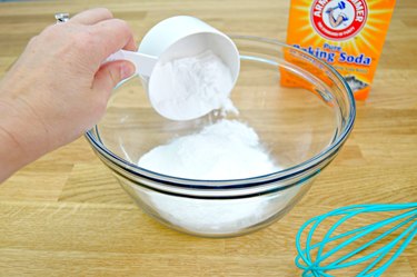 Pouring baking soda into a bowl for toilet cleaning tablets