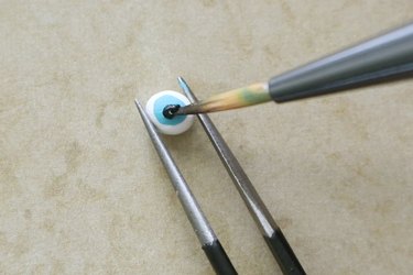 Painting eye details on white clay for potion bottle necklace