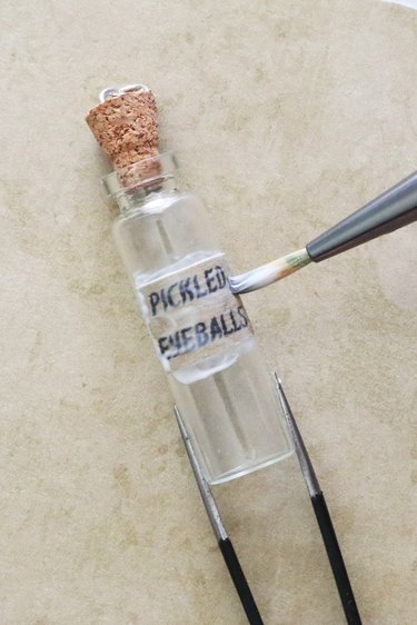 Applying potion label to bottle pendant