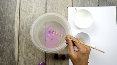 Preparing to dip nail polish marbled mugs into water.