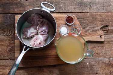 Pot with chicken with measuring cup of broth