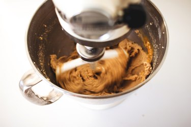 Beating eggs into a butter-sugar mixture in an stand mixer.