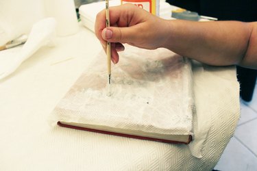 The paint brush helps to push the towel down over the objects.