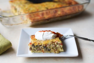 Piece of breakfast casserole with sour cream and salsa on top