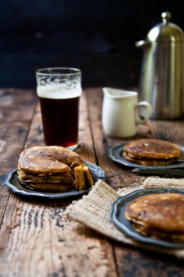 Table with plates of pancakes and pint of beer.