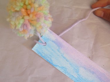 Pulling the tail of yard through the hole of a bookmark