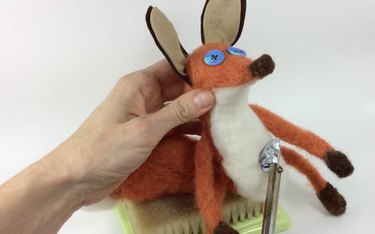 Female hands holding a needle felted fox and mini iron