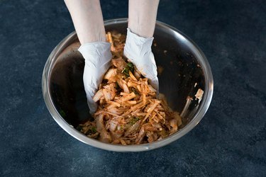 Mixing the kimchi ingredients with gloved hands