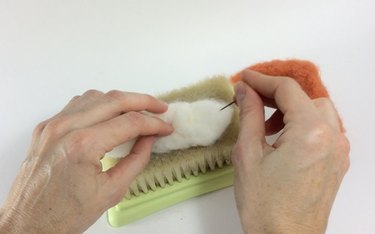 Female hands needle felting white roving on a felting pad