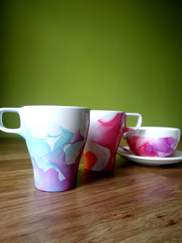 DIY Nail polish marbled mugs on table.
