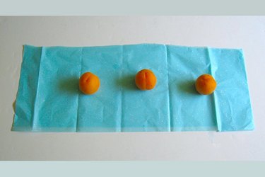 three apricots lined up on tissue paper
