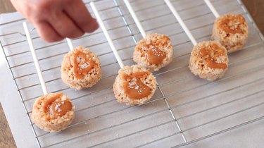 Sprinkling sea salt onto Krispies pops on wire rack.