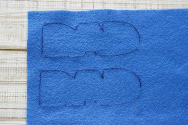 "DAD" design traced one above the other onto blue felt.