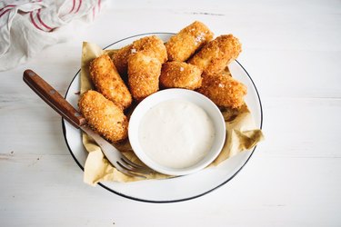 Potato croquettes on a plate with dipping sauce.