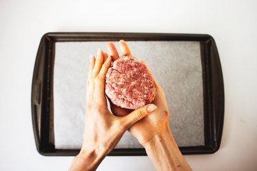 Hands shaping the beef hamburger patties.