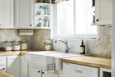 Herringbone marble tile backsplash in a white kitchen