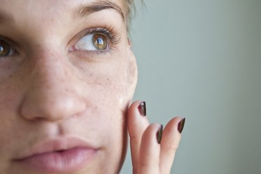 a woman touching her cheekbone prosthetic