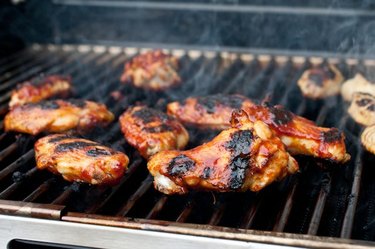 Charred chicken wings atop a steaming hot grill.