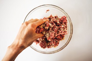 Using hands to combine the ingredients in a bowl.