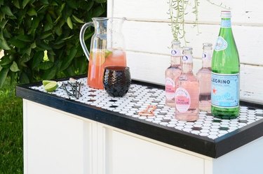 A white cabinet with a black and white tray topped with drinks