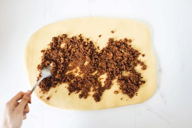 Spreading the cinnamon sugar filling over the dough rectangle.