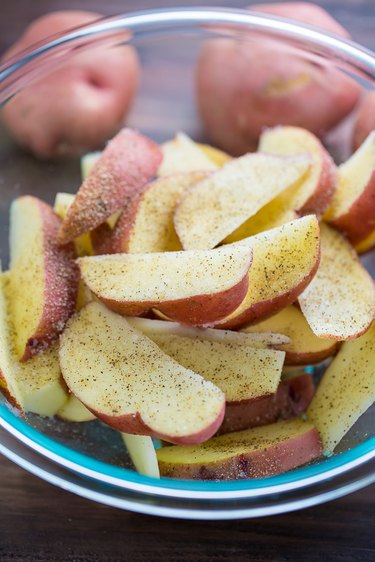 Seasoned potato wedges in a bowl, ready to cook