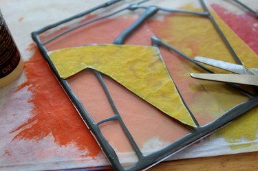 A cut out piece of melted crayon art atop the painted designs on acrylic frame