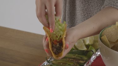 Filling taco with meat, cheese and lettuce.