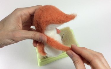 Female hands holding an orange and white fox with one arm.