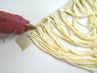 A glue gun gluing the yarn to the ribbon