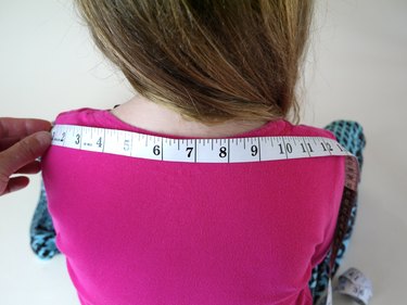 The back of a 6 year old girl with a measuring tape.