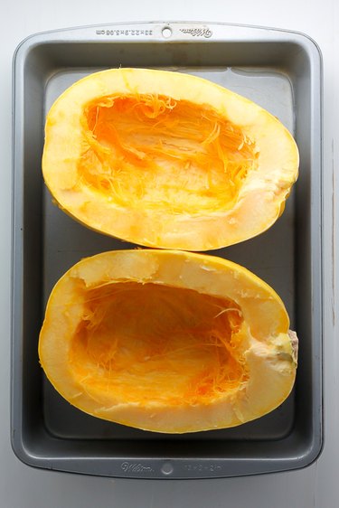Roasting pan with two halves of a spaghetti squash.