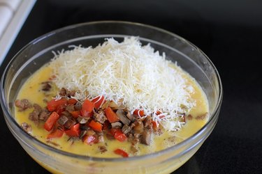 Bowl of beaten eggs, vegetables, sausage, and cheese