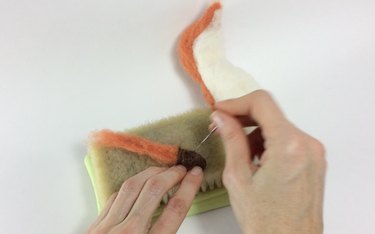 Female hands holding an orange and white fox with one arm.