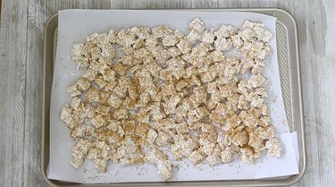 golden chex cereal spread onto baking tray