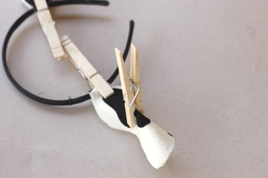 A black headband with two fabric cow ears attached, and held in a folded shape with clothespins...