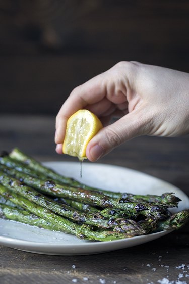 Squeezing lemon over grilled asparagus