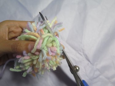 Trimming a bundle of yarn to create a pompom shape