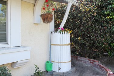 rain barrel decorated with wooden stakes and flowers