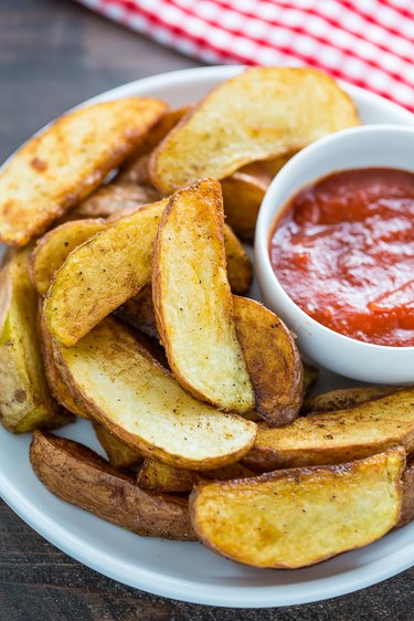 Pan fried potato wedges in a plate with ketchup