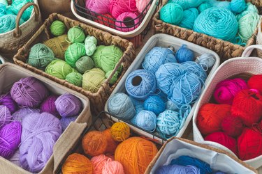 Many baskets made of natural eco-friendly materials filled with multicolor yarn for knitting and knitting needles