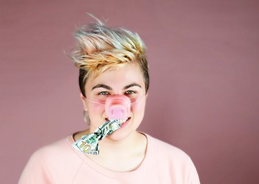 Young Adult Wearing Pig Nose with Money in Mouth