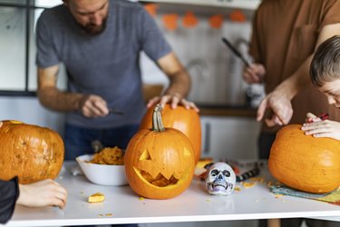 Family celebrating halloween at home and preparing pumpkins