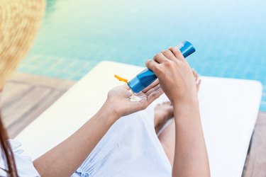 Midsection Of Woman Applying Moisturizer By Swimming Pool